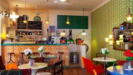 Concurrido mostrador de cafetería moderna con baristas trabajando y clientes ordenando